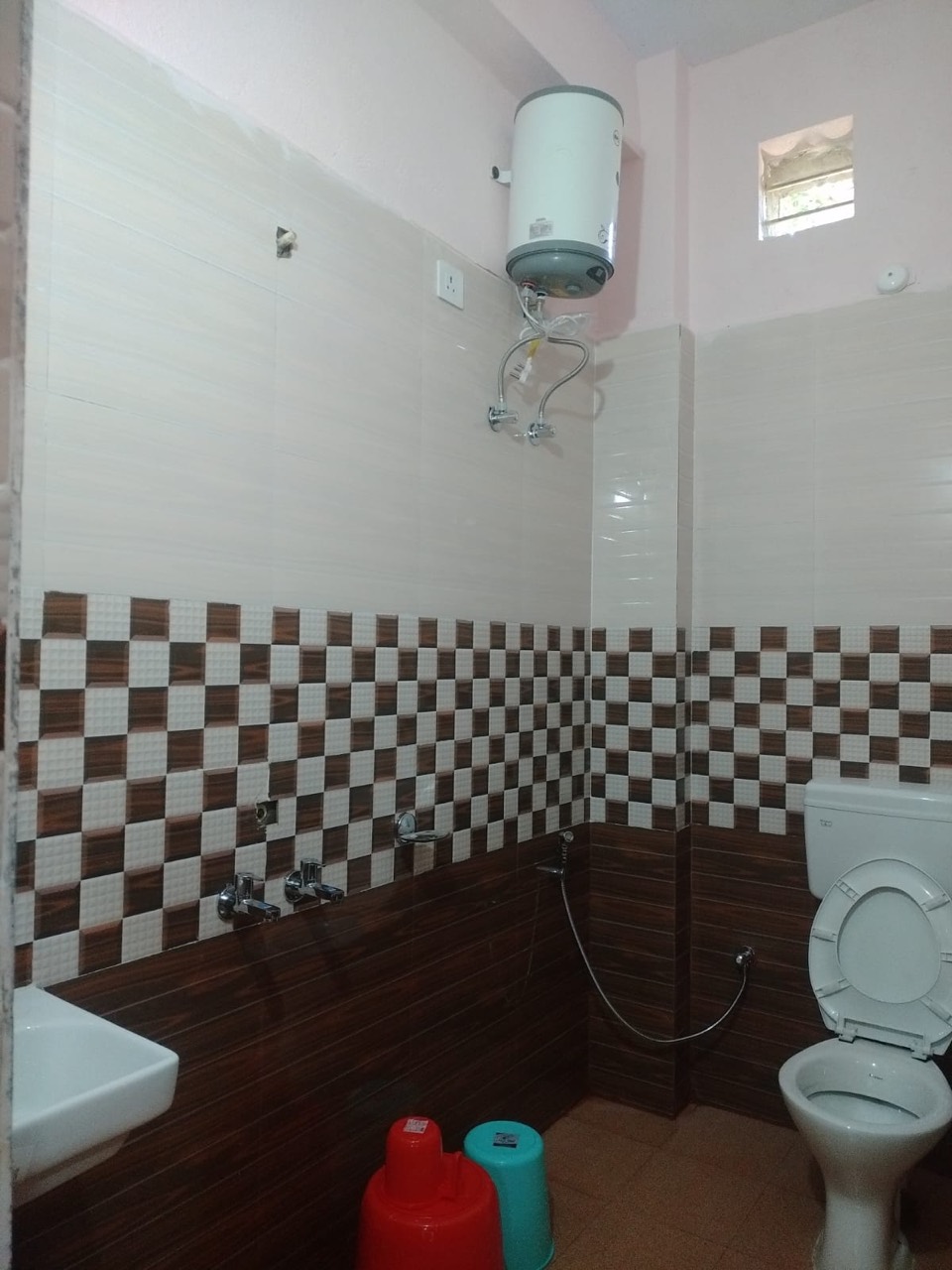 Clean tiled bathroom with western toilet and hot-water geyser