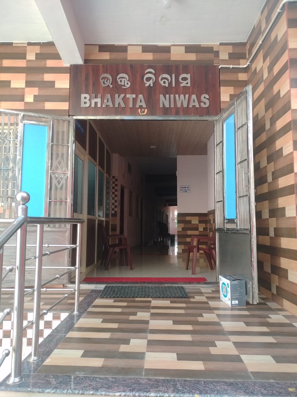 Entrance of Bhakta Niwas guest house in Koraput, with the name on a wooden signboard in Odia and English
